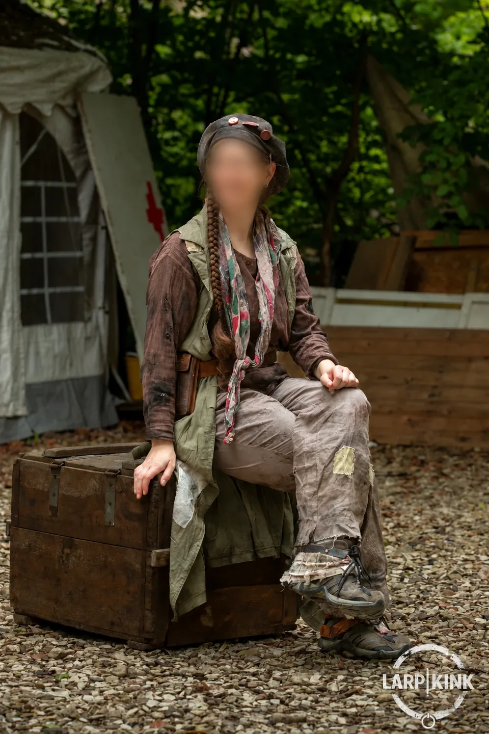 Eine lächelnde Teilnehmerin in ihrem Charakterkostüm auf einer Holzkiste